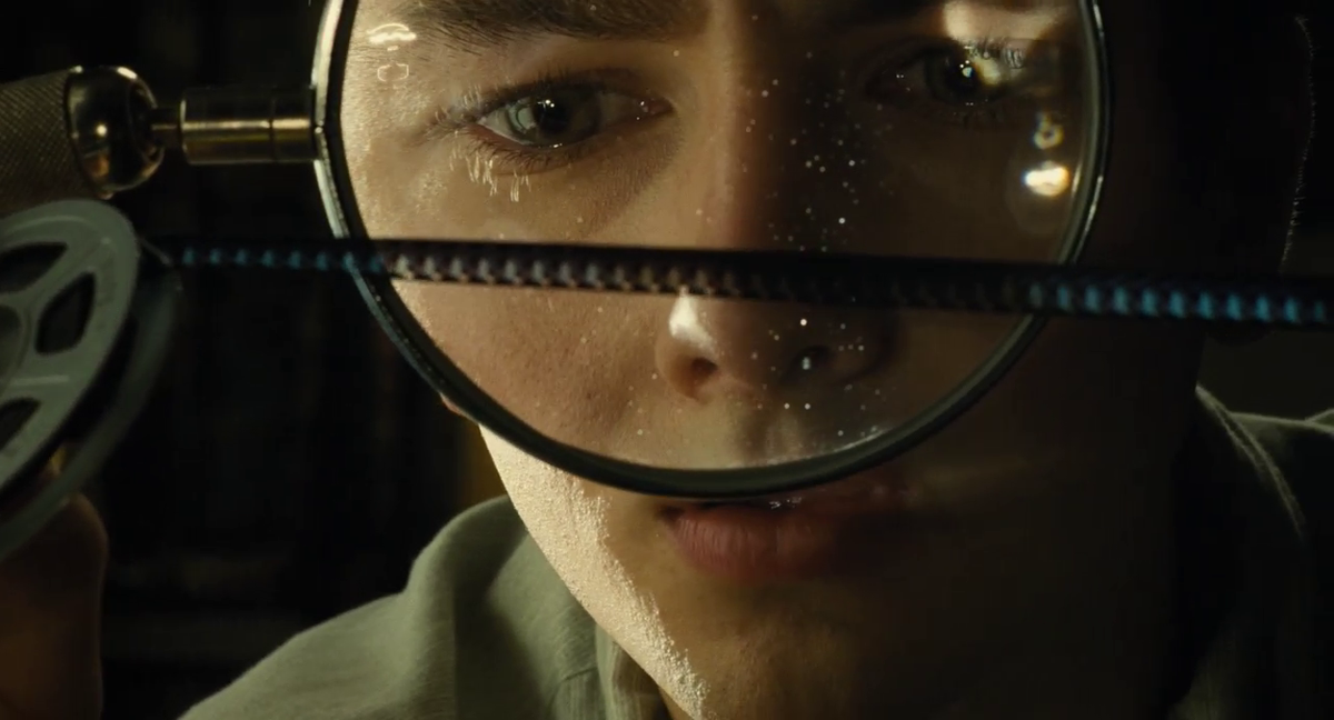 Gabriel LaBelle examines a strip of Super-8 film in THE FABELMANS.