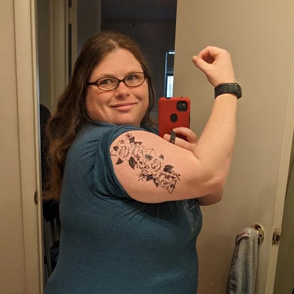 This is a photo of the author Morgan von Cross showing off a temporary tattoo on her arm of black roses.