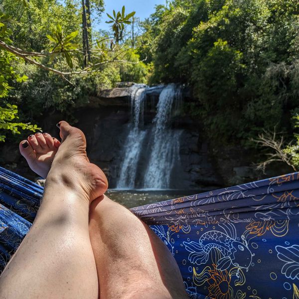 The author's feet hanging out of a blue hammock with Silver Run Falls in the background.