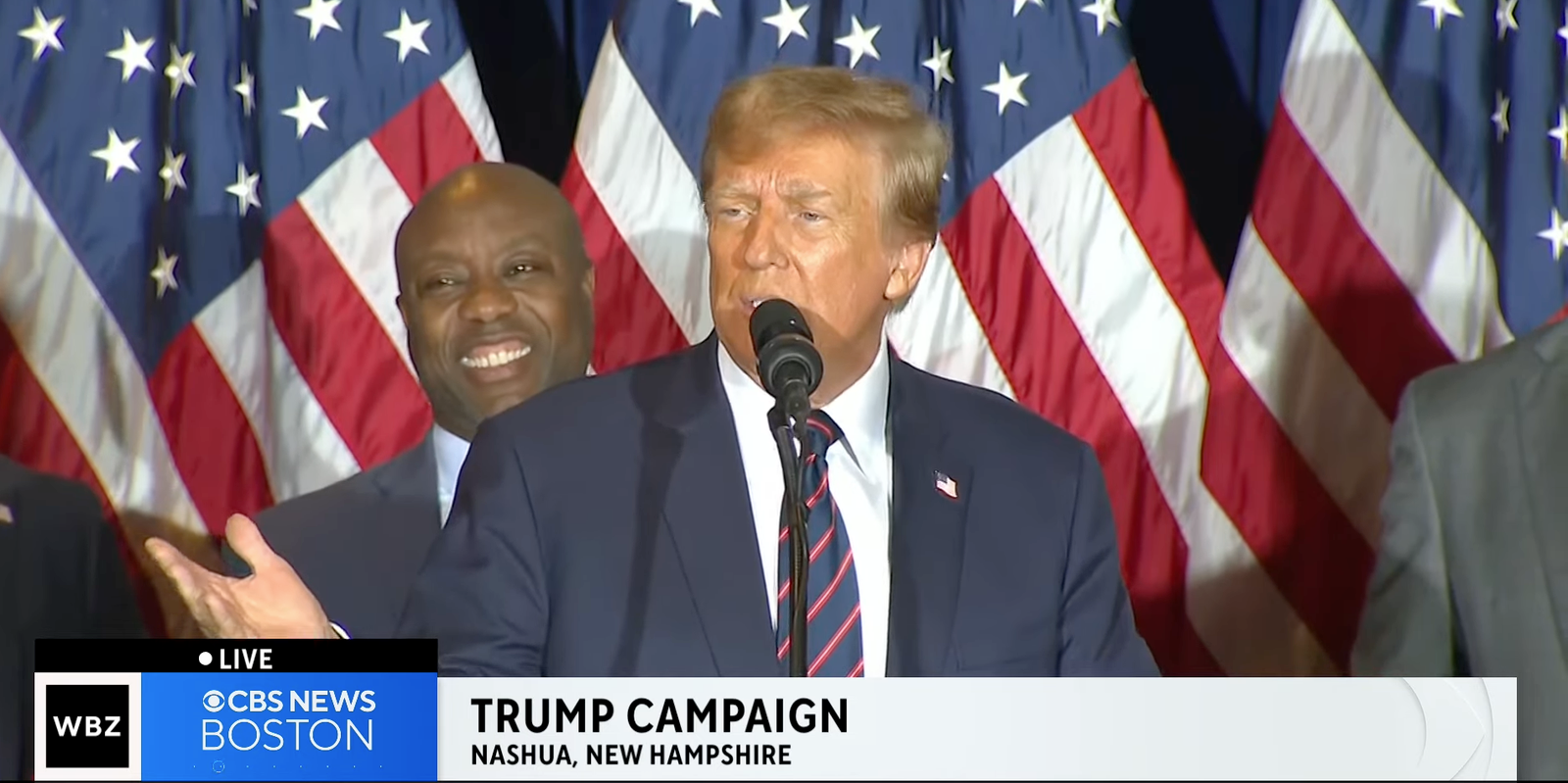 Donald Trump giving his New Hampshire victory speech with Sen. Tim Scott in the background. Screenshot: CBS 