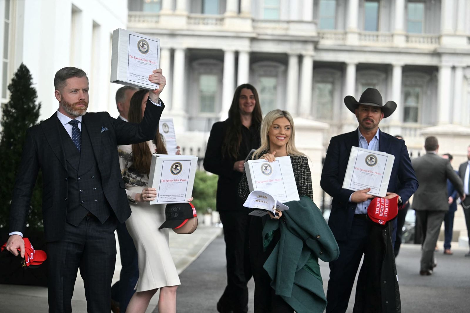 Conservative political commentators carry binders reading "The Epstein Files: Phase 1" outside of the White House in February | Jim Watson/AFP via Getty Images