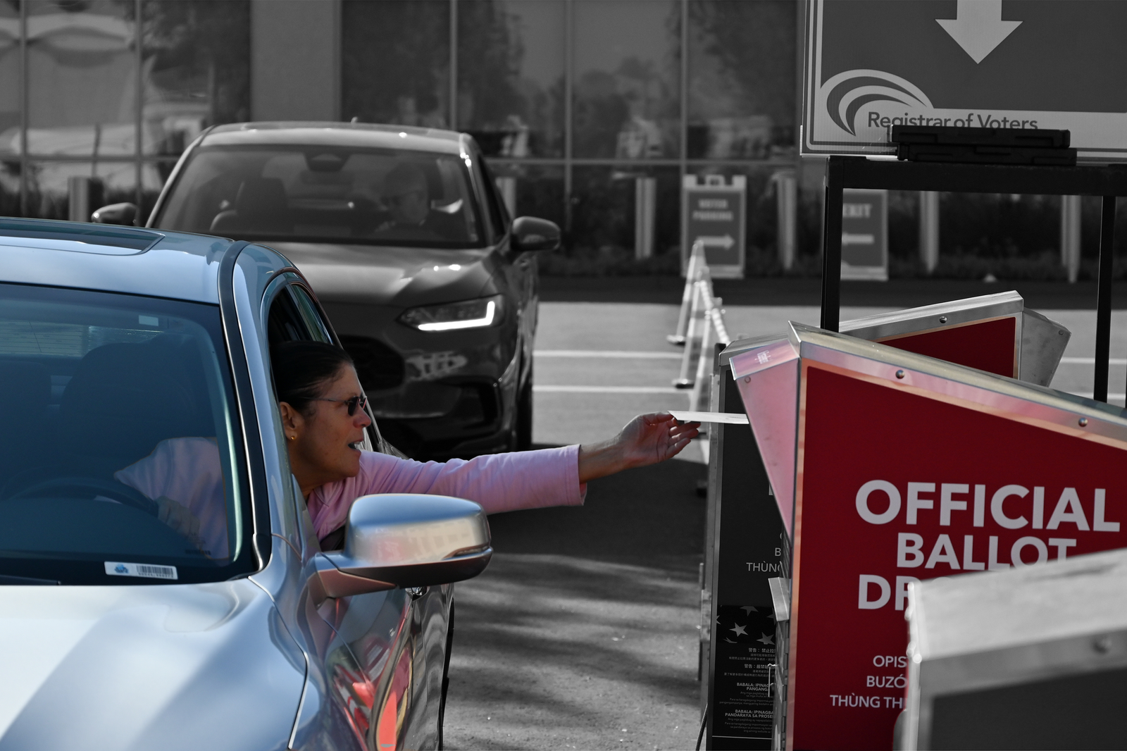 A voter drops her mail-in ballot off via car in San Diego | Photo by Carlos Moreno/NurPhoto, edited by Russell Nystrom