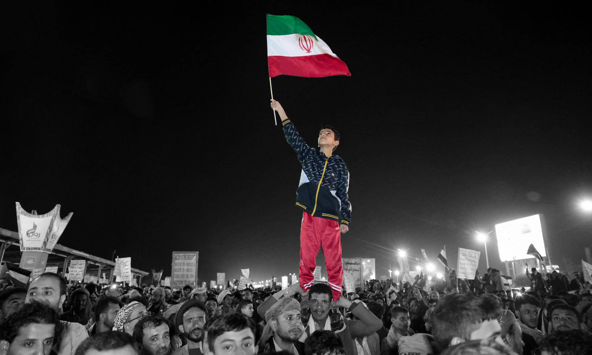 A boy waves an Iranian flag as he demonstrates against airstrikes in Yemen | REUTERS/Khaled Abdullah, edited by Russell Nystrom
