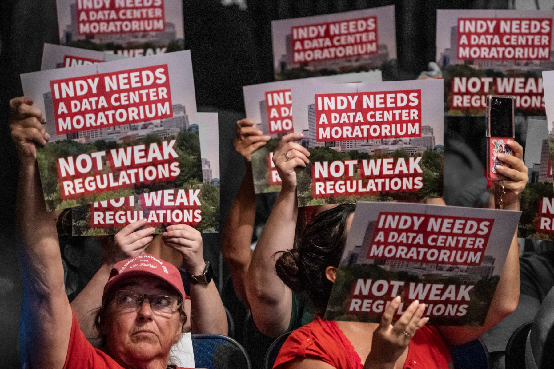 Members of the public hold protest signs reading "Indy needs a data center moratorium. Not weak regulations" during an Indianapolis Metropolitan Development Commission meeting.