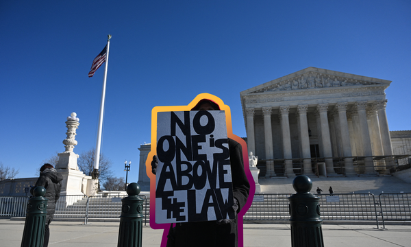 A woman holds a sign reading "No one is above the law" in front of the Supreme Court as it hears oral arguments on whether President Trump can fire Lisa Cook