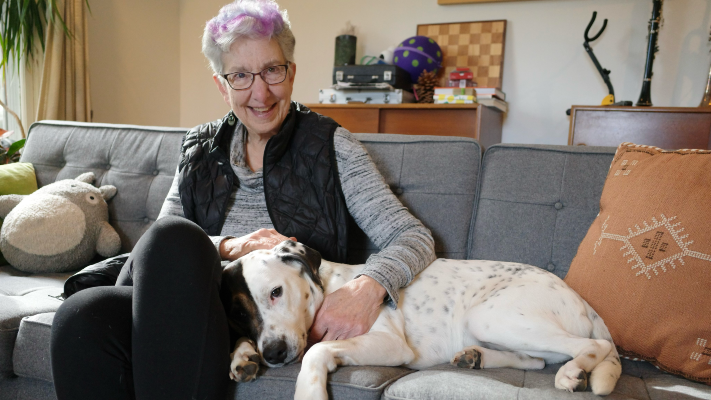 My mom, on a couch, with a cute dog snuggling her