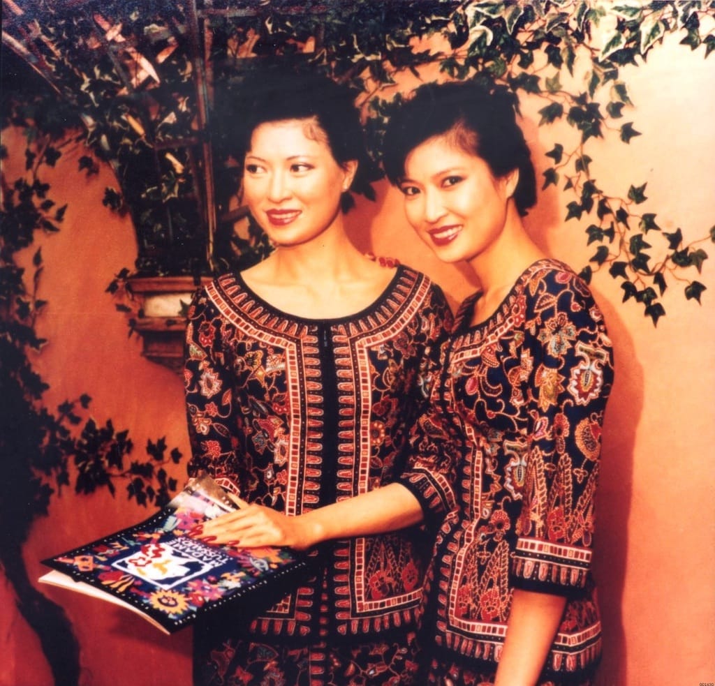 Close portrait in blue kebaya, shadows soft across fabric and collarbone. Posture upright. Eyes off-frame.