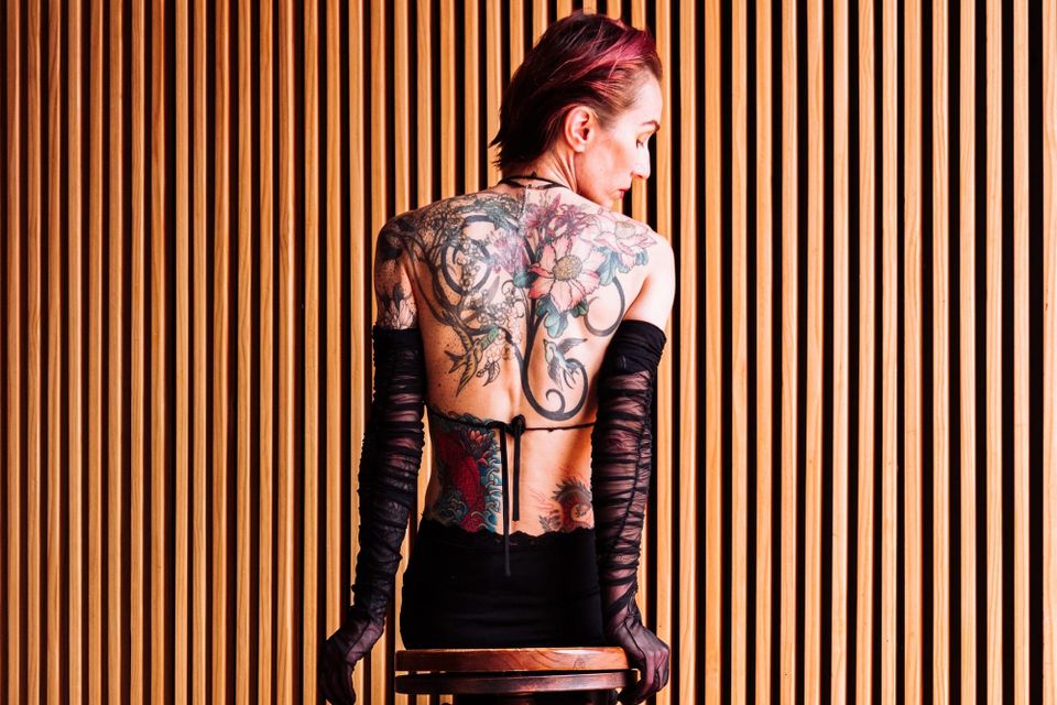 Close-up of a tattooed upper back, photographed in soft light. 