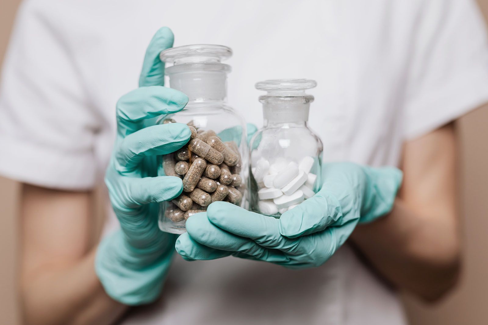Pharmacist holding glass bottles with white tablets and brown capsules for inventory tracking concept