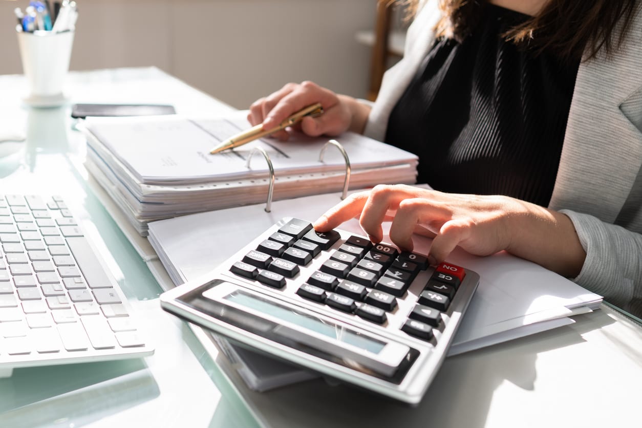Professional Accountant Woman In Office tapping on a calculator at her desk
