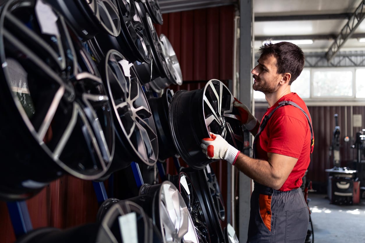 Man at an auto shop managing car parts (tires)