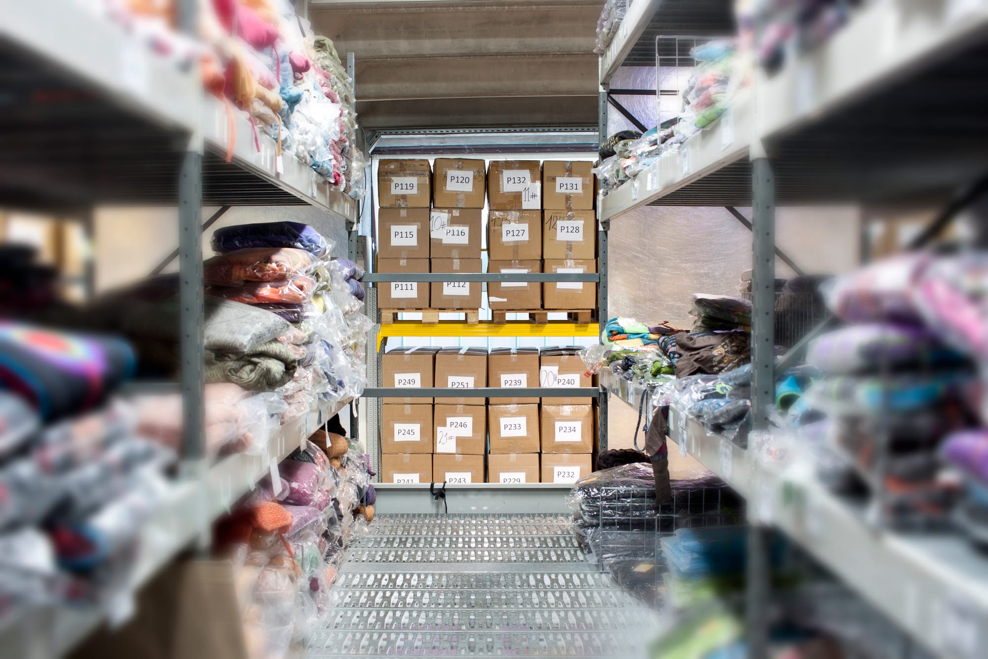A part of wholesaling warehouse with clothes on the shelves and stored numbered boxes.