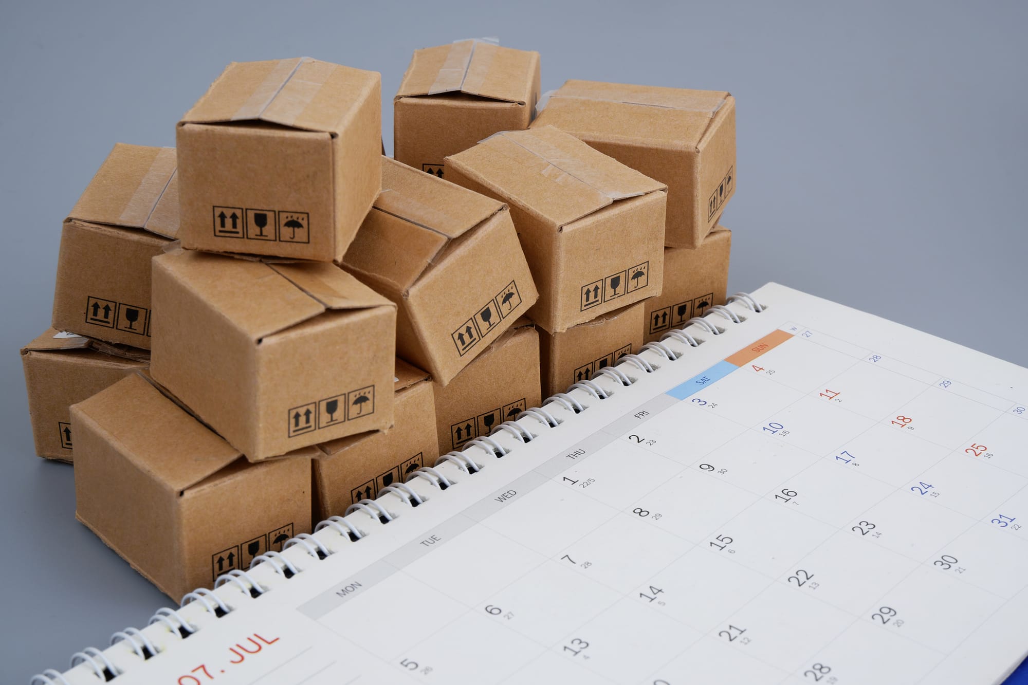 Delivery day and shipment time concept with carton boxes and calendar.