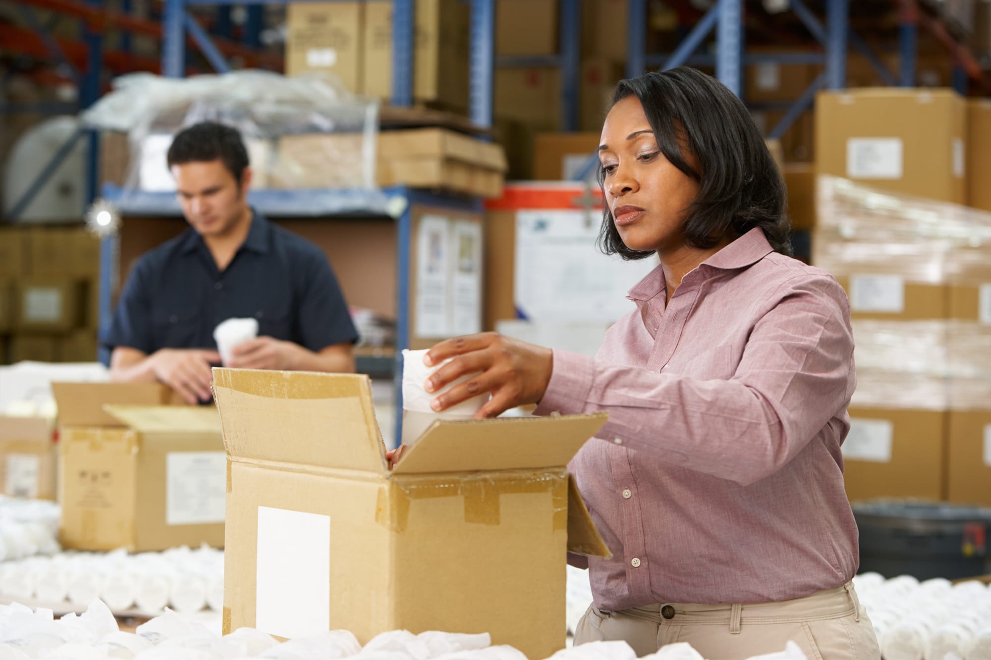 Warehouse workers packing products into boxes during the order picking and kitting process