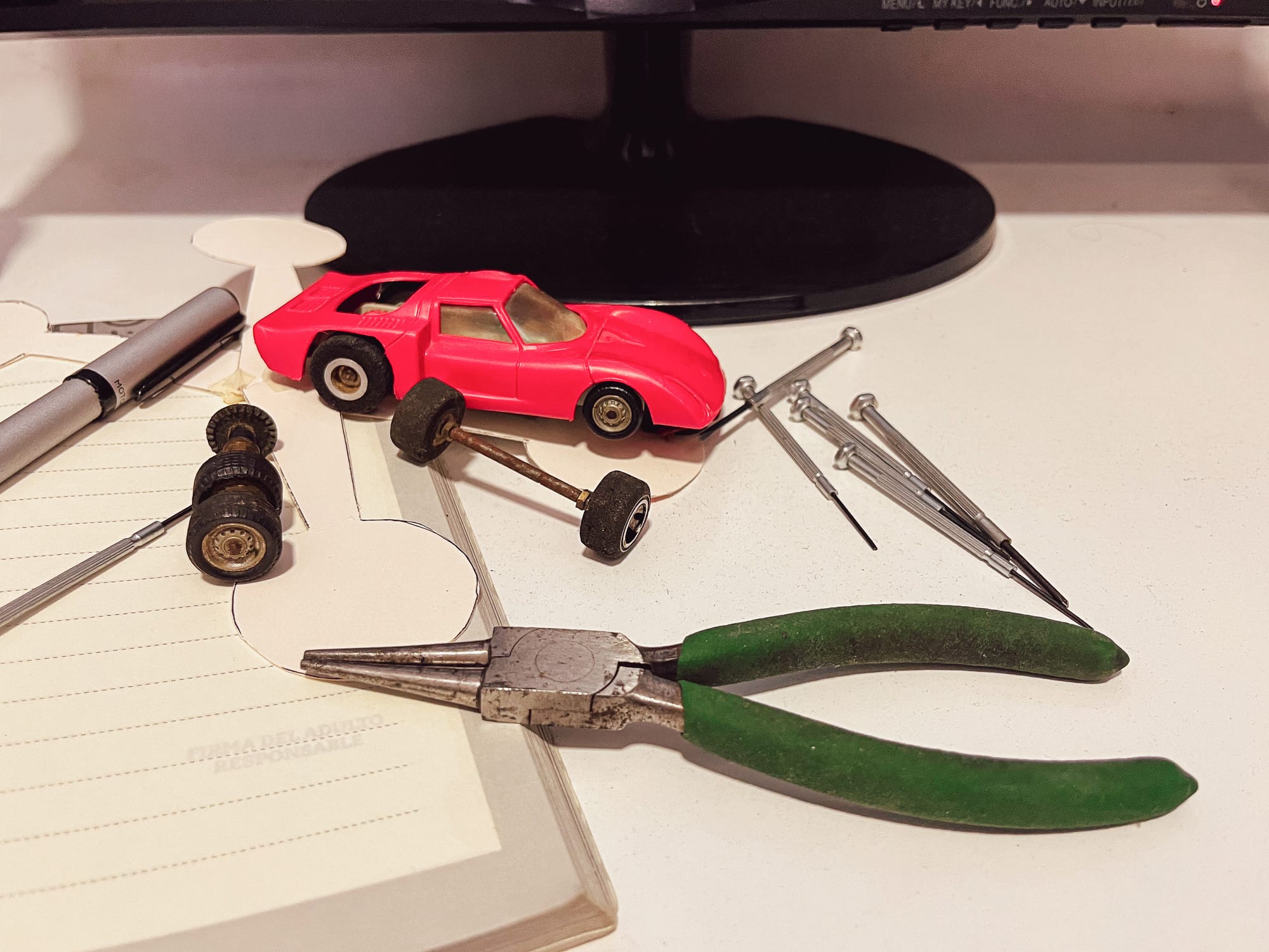 A model car beside its separate wheels, axles, and assembly tools, showing components grouped before assembly