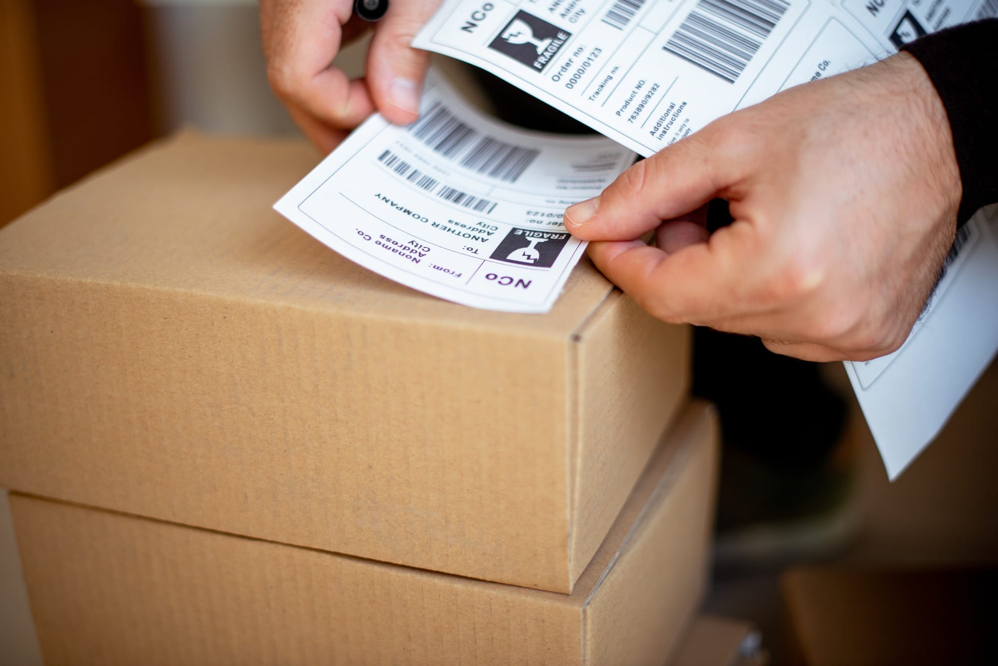Applying a shipping label to the left of a packaged box 