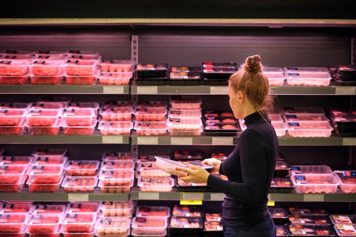 Woman purchasing a packet of meat at the supermarket