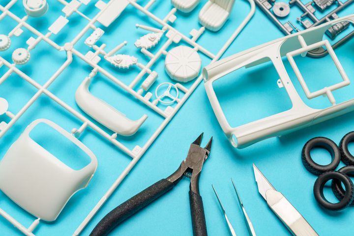 Plastic model car kit parts on sprues with cutters and tweezers, an example of components packaged as one kit