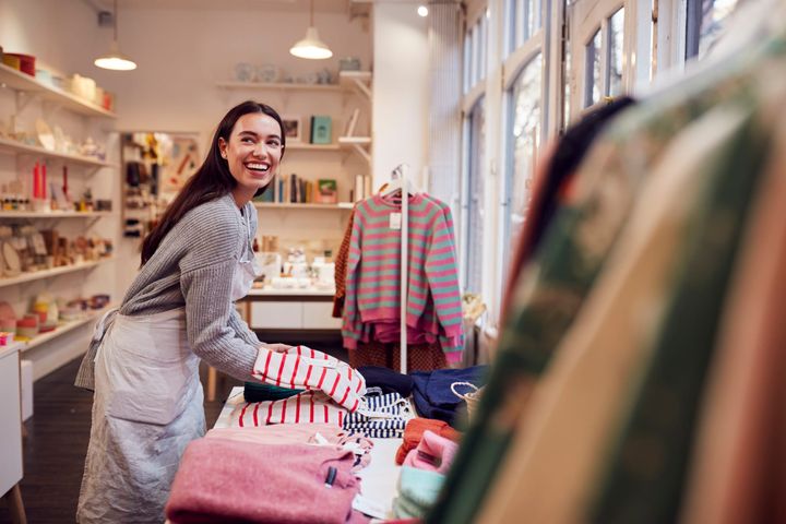 Female Small Business Owner Arranges Stock In Window Display