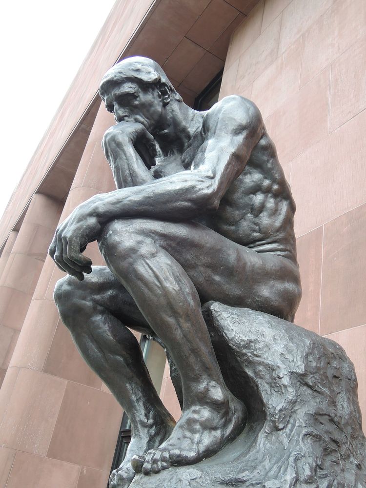 A bronze statue of a naked man thinking pensively. It's Rodin's "The Thinker."