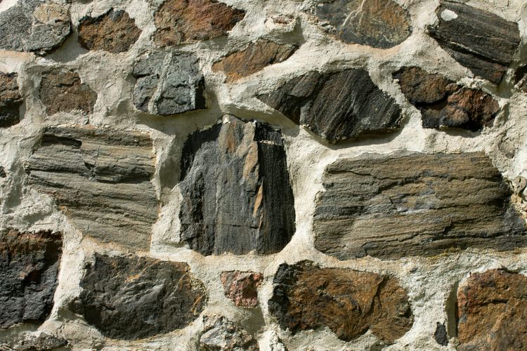 Variously sized pieces of grey and reddish stone held together by white mortar.