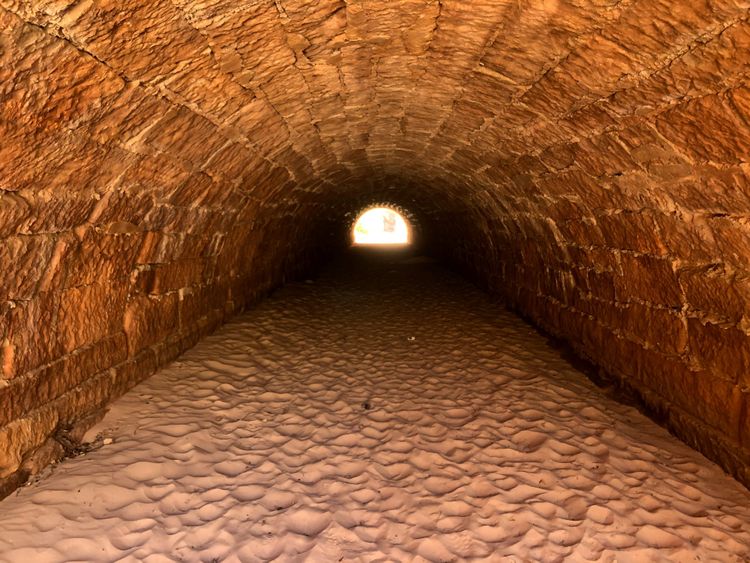 A tunnel of sand and stone, with a golden light at the far end.