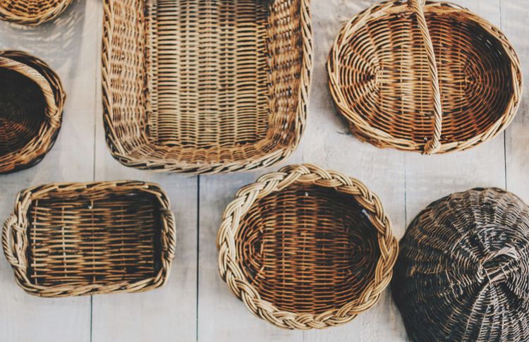 About half a dozen wicker baskets of various rectangular or round shapes, some with handles or lids.