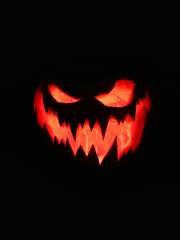 A very jagged-toothed jack o' lantern face is lit up with minimal other lighting.
