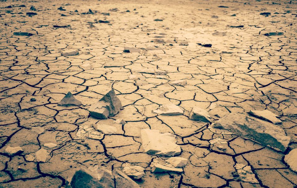 A cracked clay ground surface, as of a dry river or lakebed, in sepia tones.