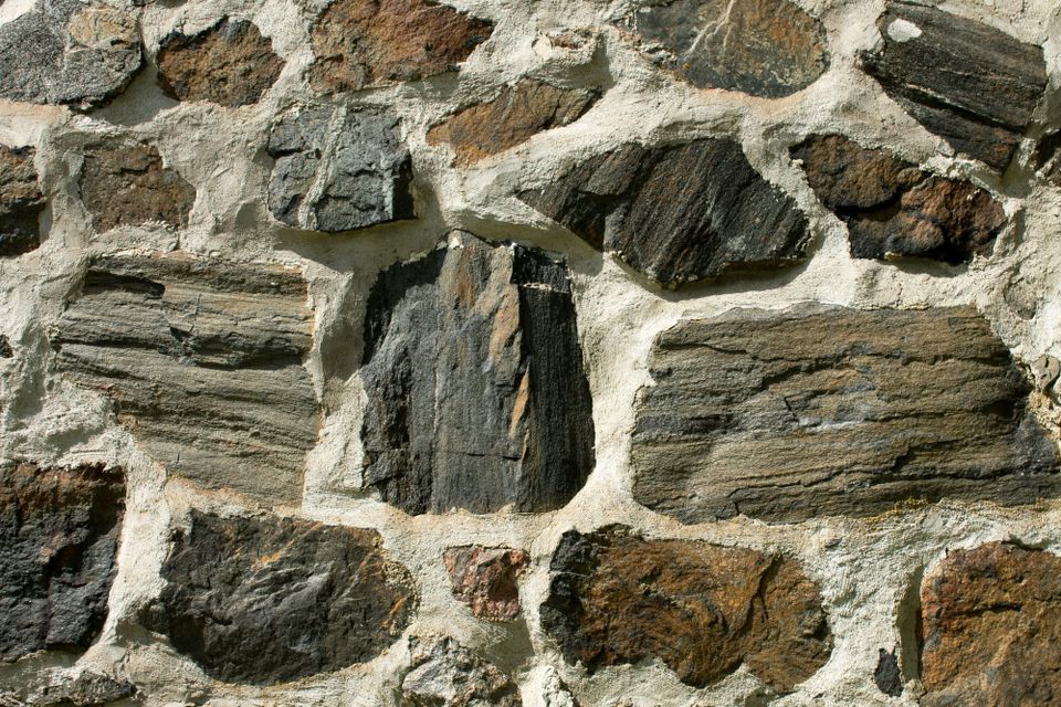 Variously sized pieces of grey and reddish stone held together by white mortar.