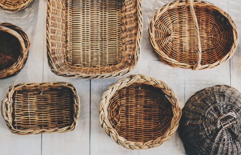 About half a dozen wicker baskets of various rectangular or round shapes, some with handles or lids.