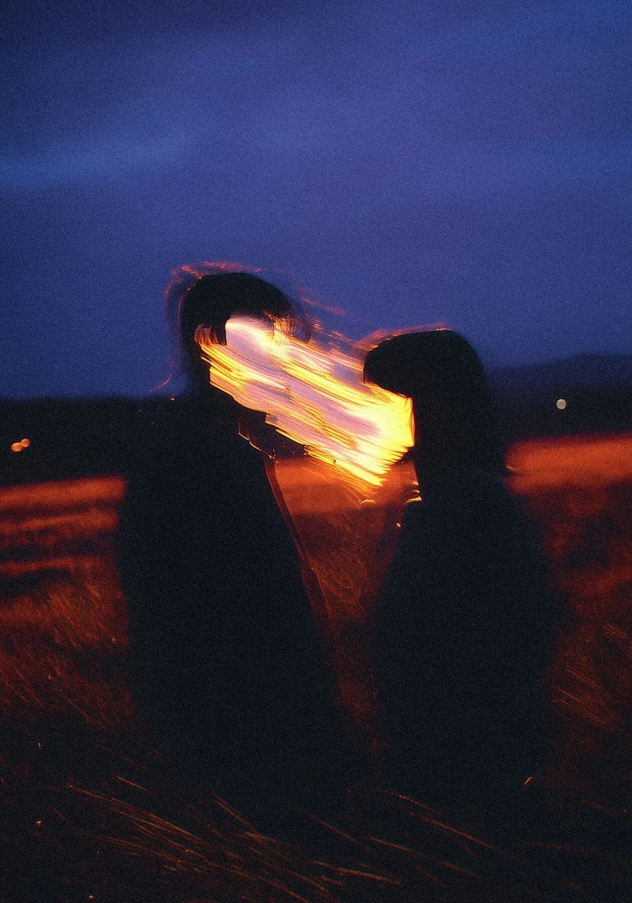 Fire streaking between two silhouetted figures at dusk — Vagabond Diary