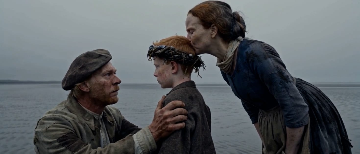 A mother kisses the head of a boy wearing a seaweed crown while a fisherman holds his shoulder, a still from Brine