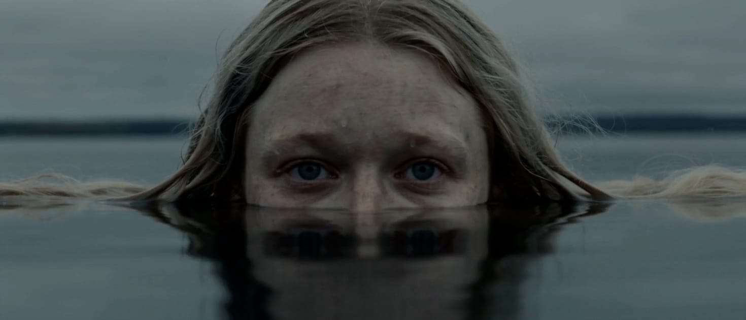 The mermaid's eyes just above the surface of still grey water, a still from Brine