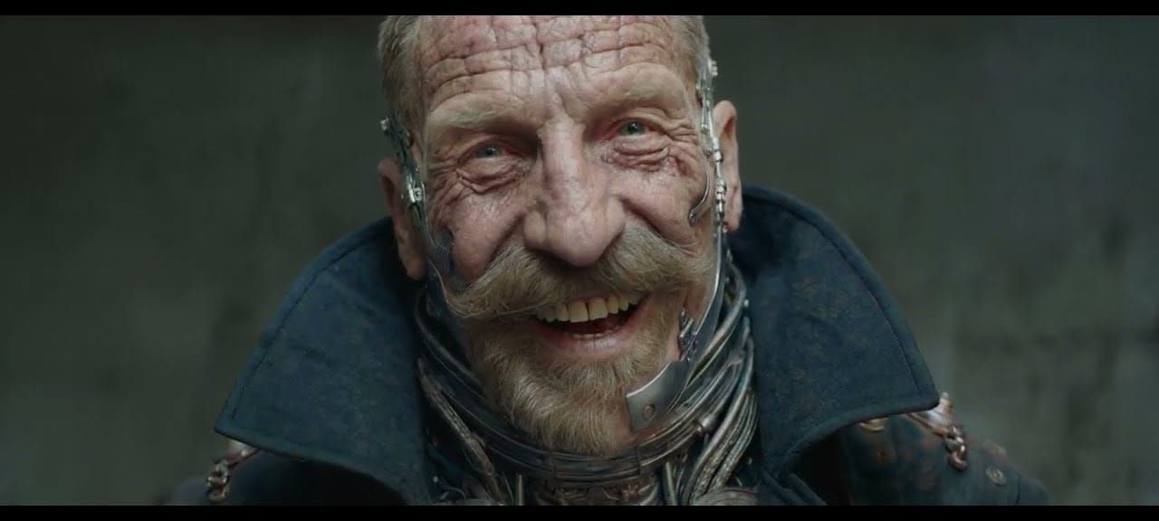 Laughing older man with cybernetic implants on his face and neck, from Gossip Goblin's film The Patchwright