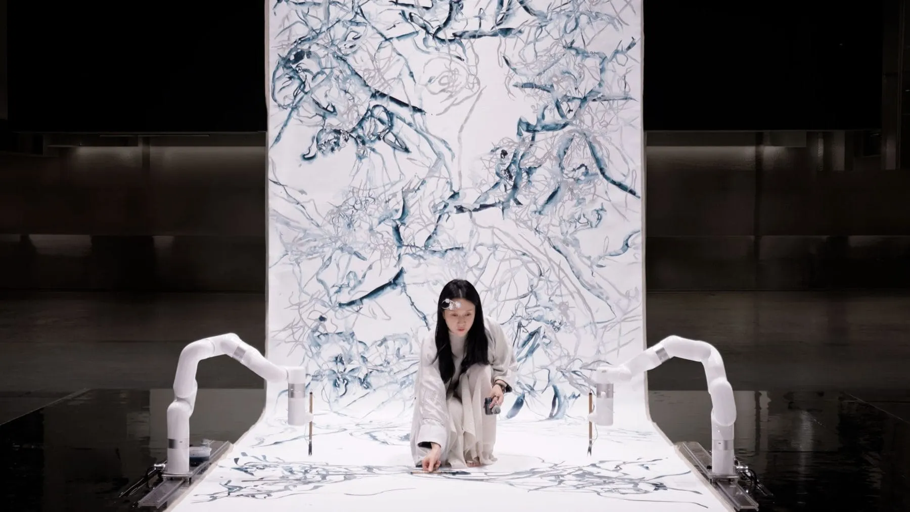 Artist Sougwen Chung collaborating with a robotic arm to create large-scale generative drawings on canvas