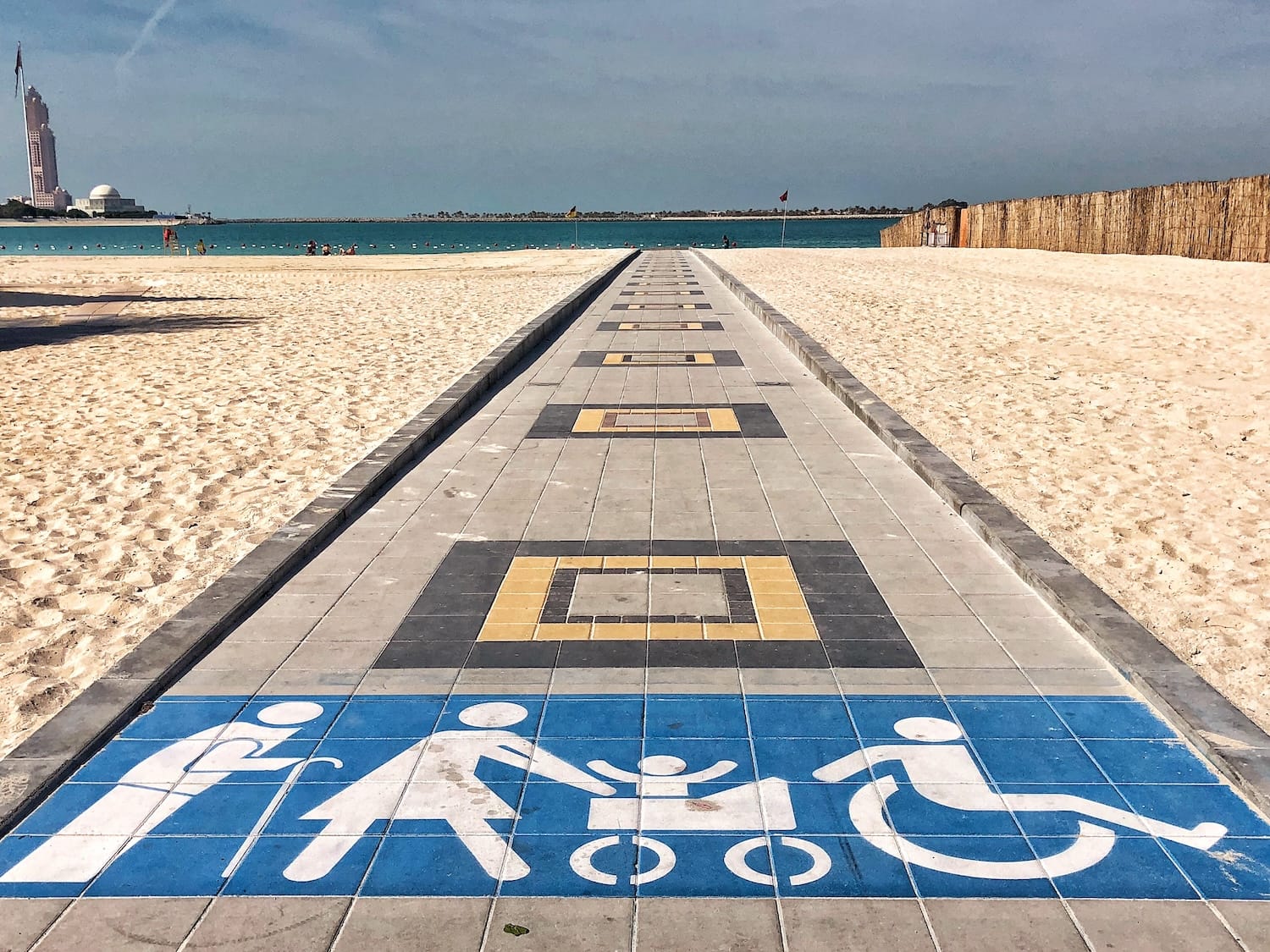 pathway on sand at the beach with elderly, woman with pram, and wheelchair user