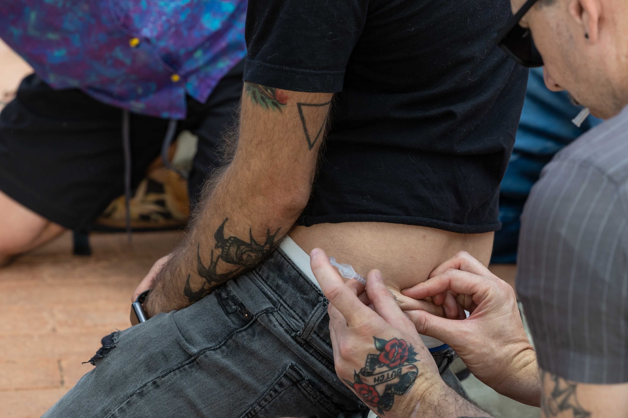 Someone is administering an injection into another person's abdomen.