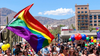 A crowd of people are smiling in the streets of Arizona as they gather with colorful balloons and rainbow flags