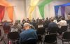 A group of people sitting at what appears to be a townhall, possibly related to Phoenix Pride Community.