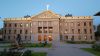 Front view of the Arizona State Capitol building at dusk with illuminated archways and a central dome.