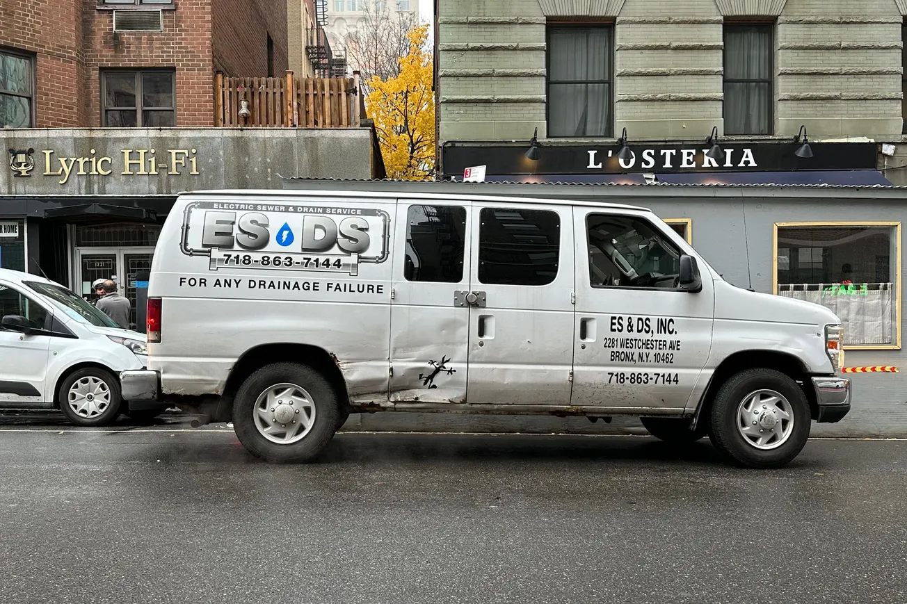 A white van in Manhatt with the outline of Wiley E. Coyote in a big dent on the side door.
