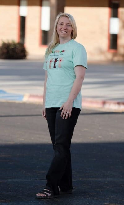 Image of woman in Everyone is Welcome Here t-shirt on parking lot in front of school building