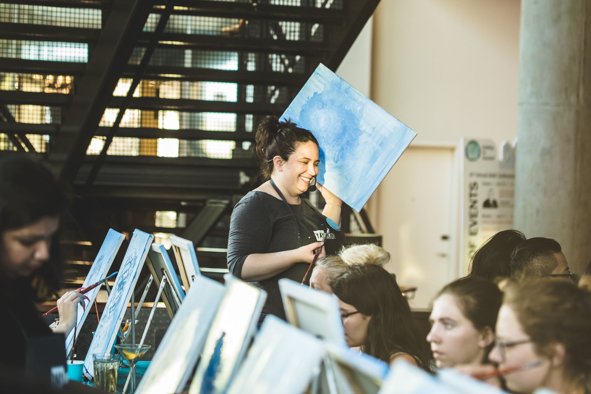 Paint Nite host holding canvas at paint and sip event