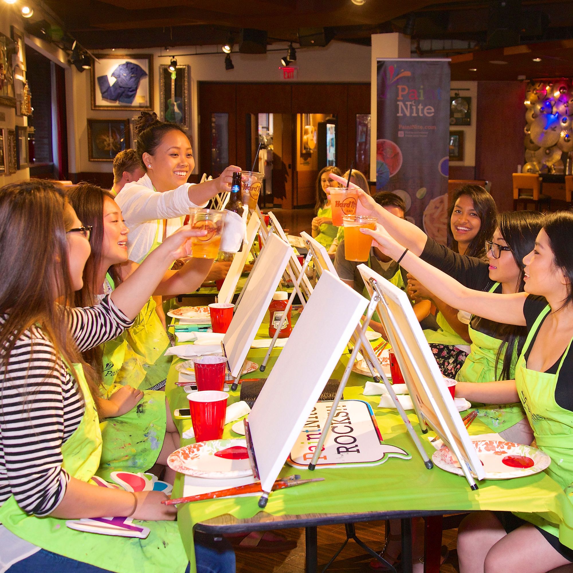 Group of girls cheer-sing at a Paint Nite event at the Hard Rock Cafe.