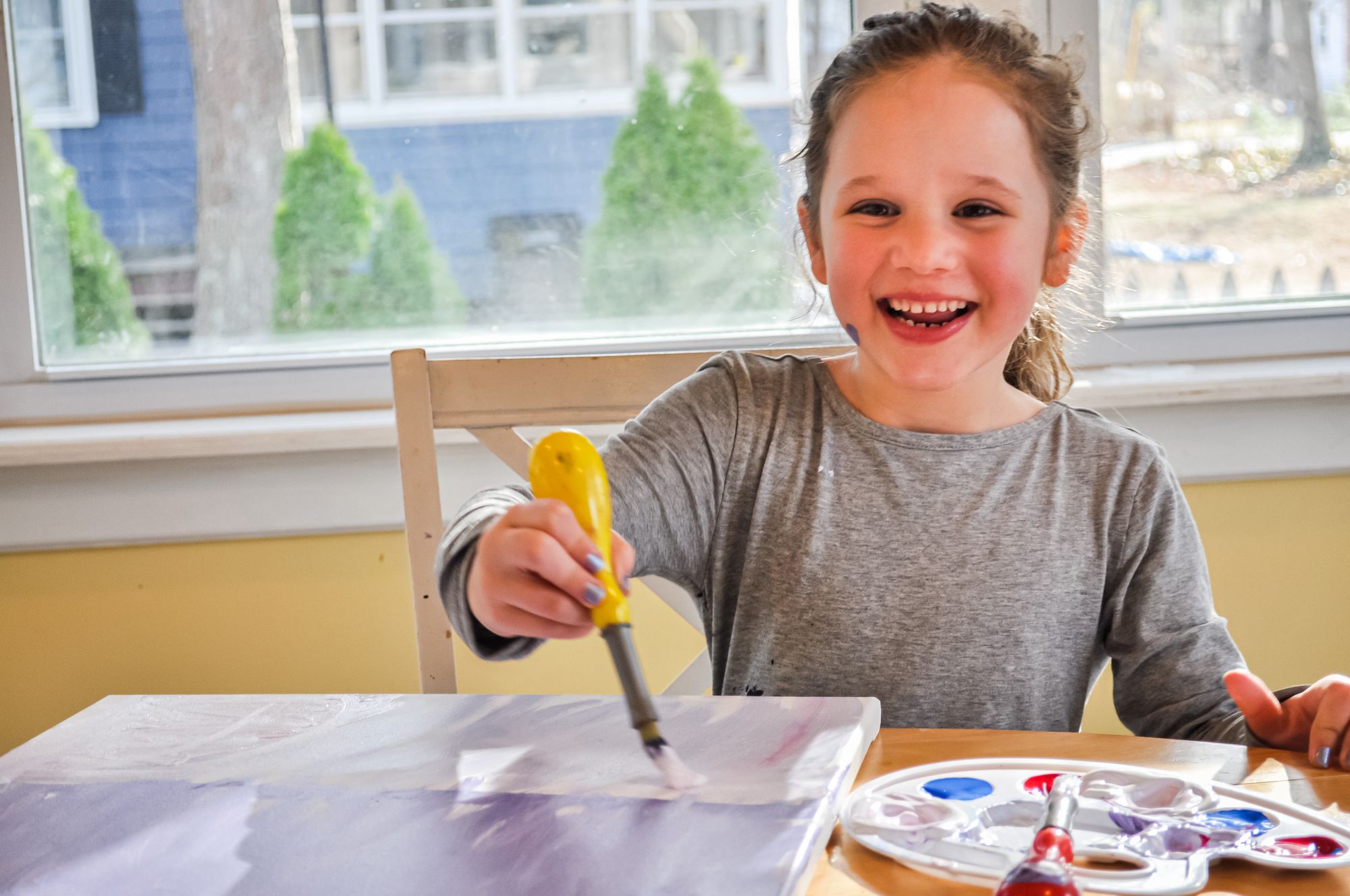 Girl smiling as she takes part in a kids Paint Nite at home