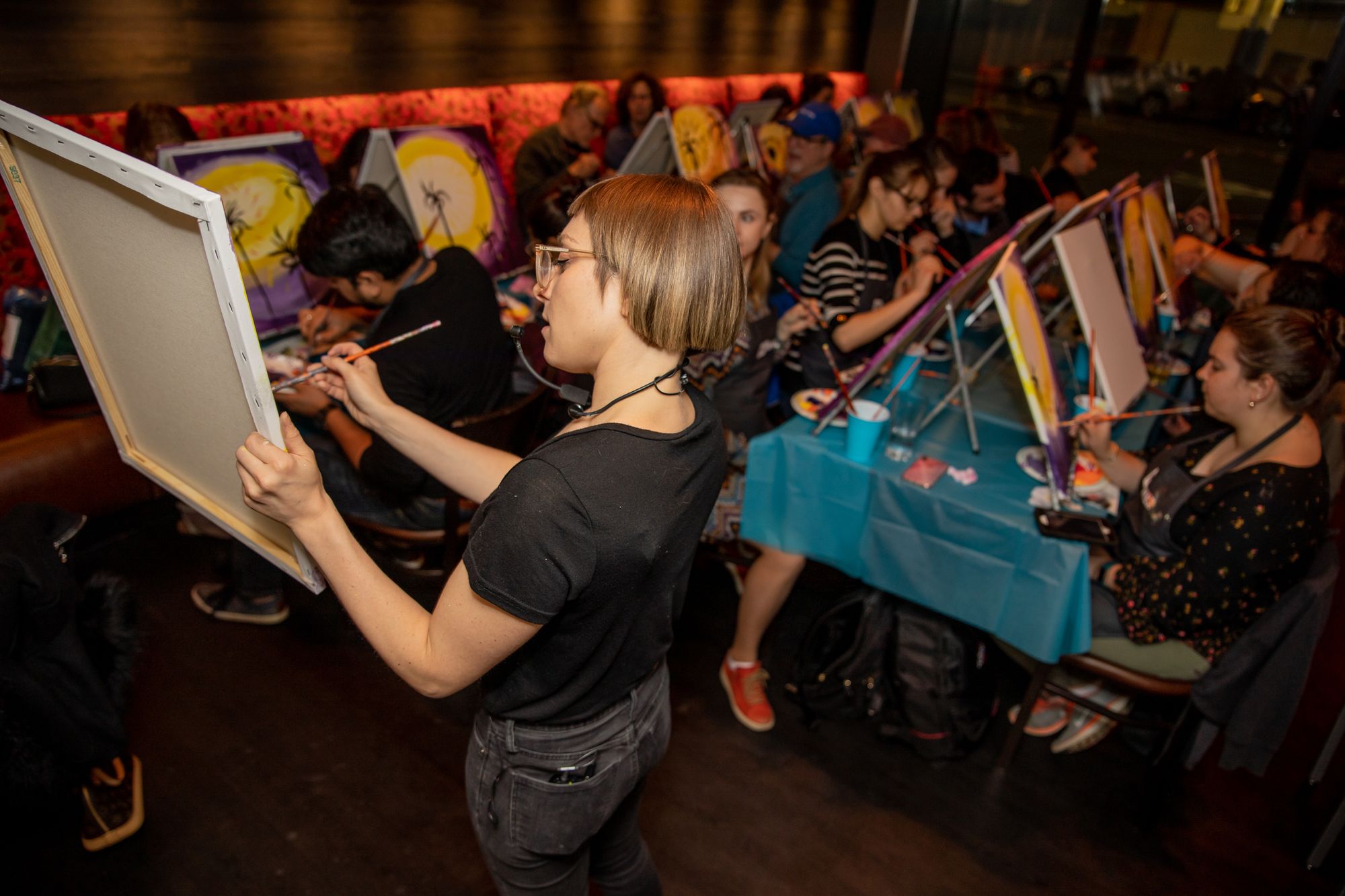 Paint Nite host leading a paint party in a bar