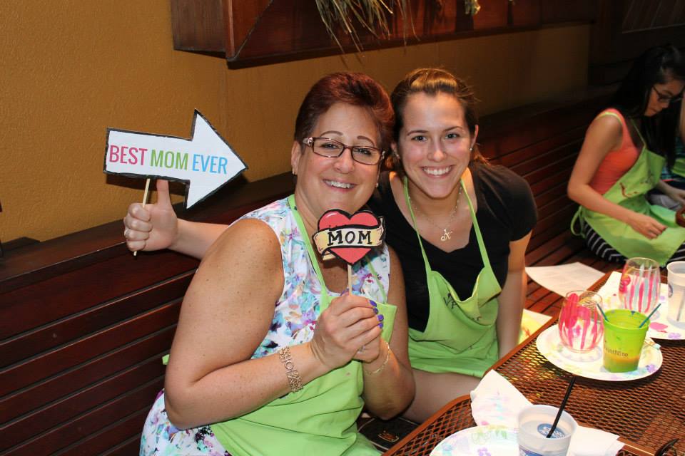 Mom and daughter painting stemless wine glasses with best mom ever sign