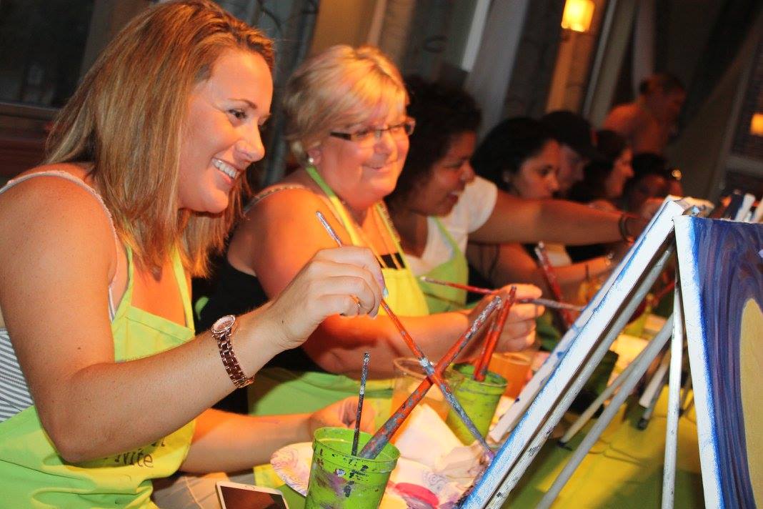 Group of women smiling and painting at Mother's Day paint party