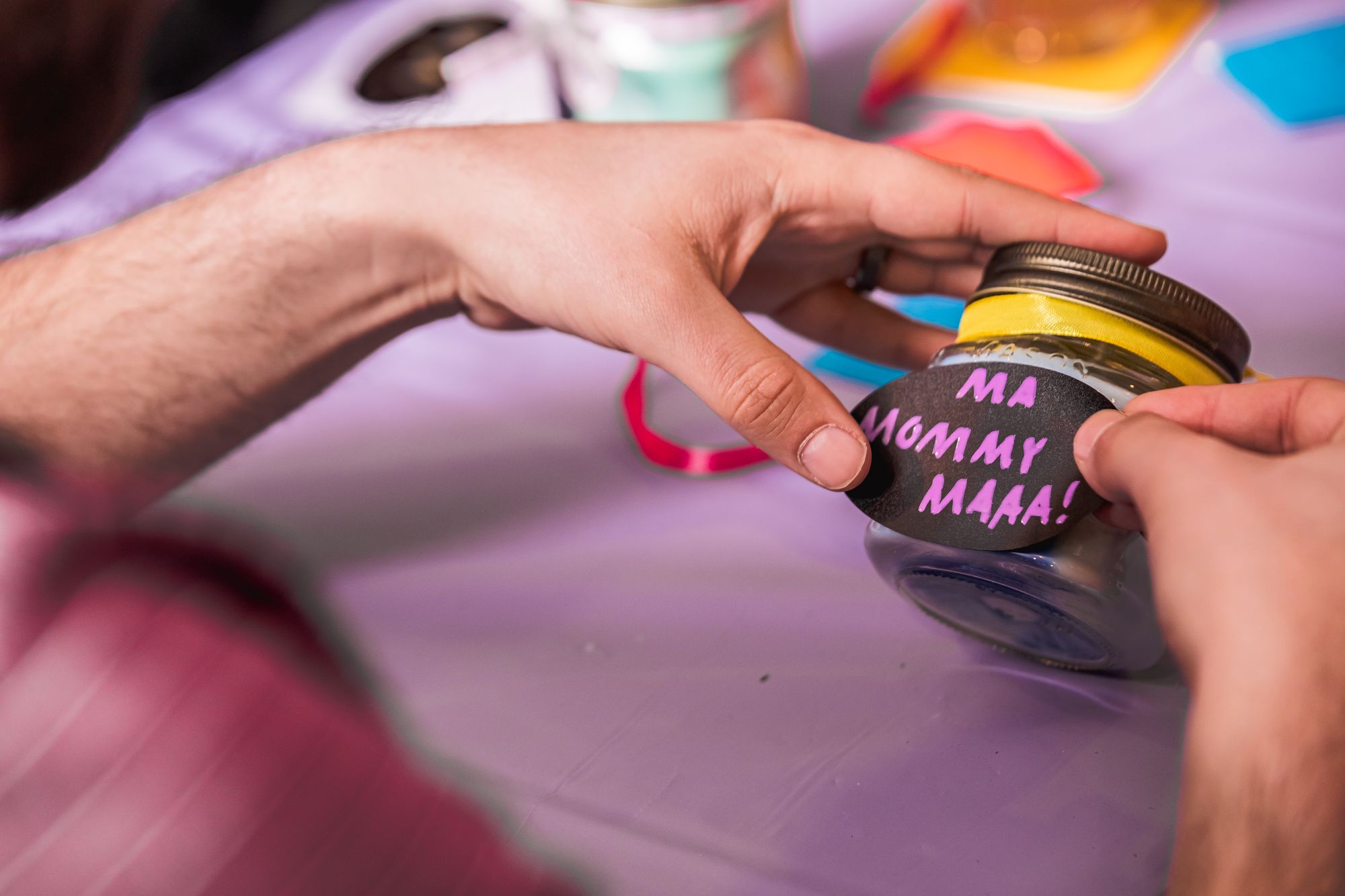 Man's hands applying sticker to jar at Mother's Day candle making event